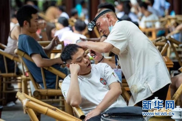 2021年6月30日,在成都市人民公园内的鹤鸣茶社,一名茶客在喝茶时享受“采耳”服务。新华社记者沈伯韩 摄