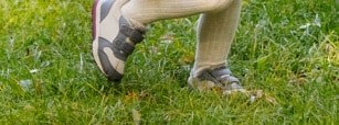 A child's feet walking through grass.