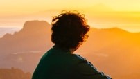 Rear view of a person looking at a sunset.