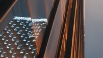 Close-up of glass building showing the reflection of another building with all its lights on.