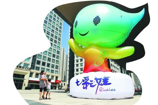 市民在万达广场上的“七彩娃”面前合影留念。杨宁/摄