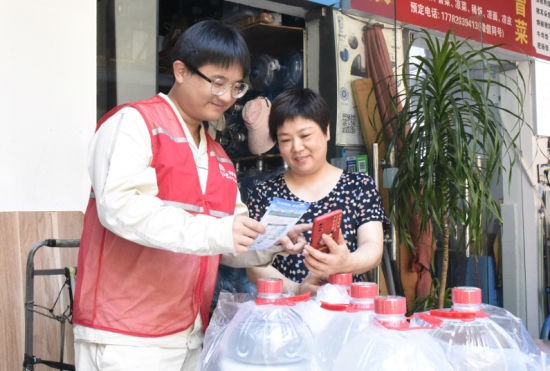 图为国网重庆市北供电公司员工在渝北区锦绣社区为居民介绍网上国网“e起节电”活动。钟雪 摄