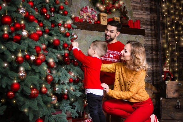 Jóvenes padres con su hijo decoran árbol de Navidad