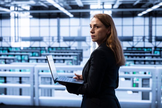 Data center computer scientist ensuring safety and security of database using notebook. Cybersecurity specialist in server farm preventing unauthorized access posing risks for business