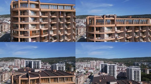 现代住宅高层建筑的鸟瞰图，带有阳台和户外区域。公寓的干净几何设计突显了现代城市生活。镜头使用无人机拍