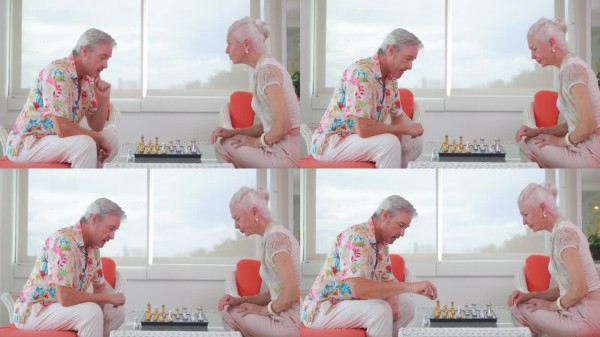老年夫妇在家里一起下棋，享受着充满策略、陪伴和轻松退休生活乐趣的宁静时光。