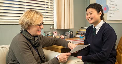 An international student and her host mother are working together to complete some paperwork and homework