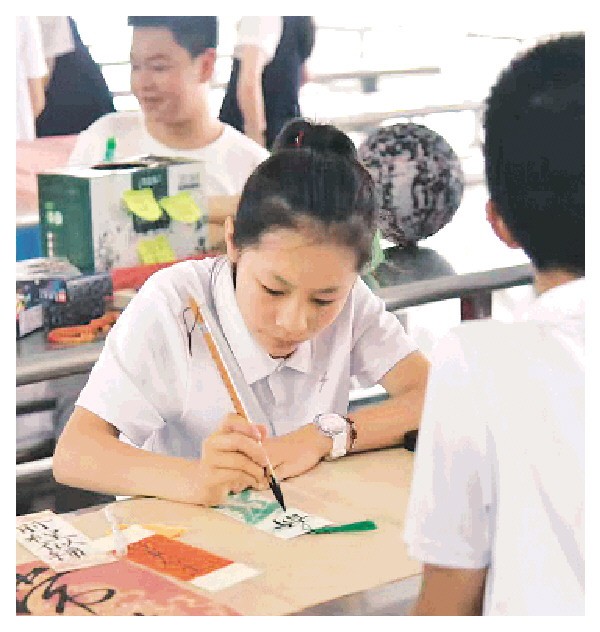 一位同学正在售卖的商品上展示书法。 (中隐小学校供图)