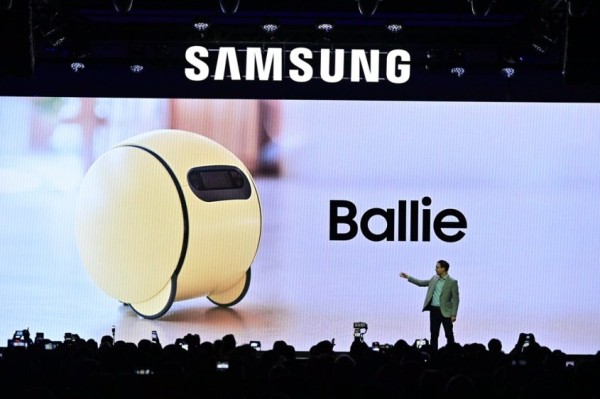 A person standing on stage with a large screen Description automatically generated