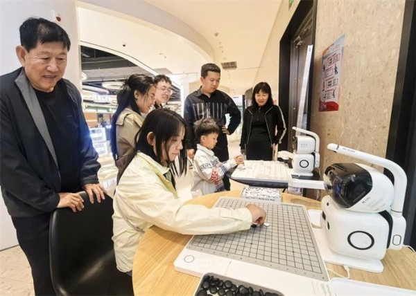 5月6日晚,雄安商服会展中心地下商业环廊内,市民正在和机器人下五子棋。 河北日报记者 李 畅摄