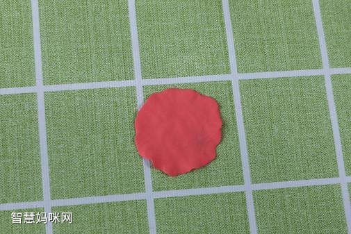 步骤7：下面开始做康乃馨，把大红色粘土压成不规则的圆片。