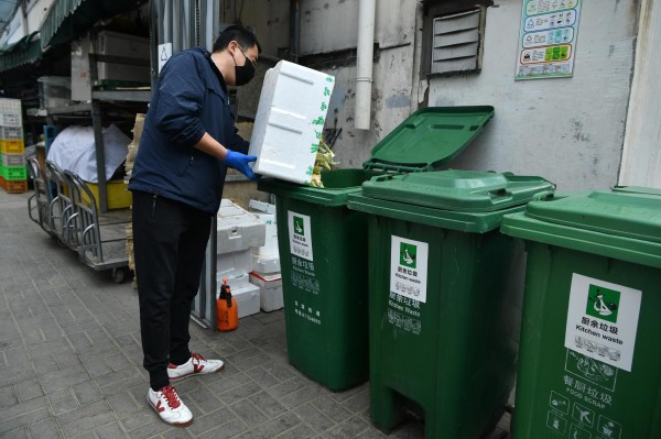  超市工作人员将果蔬垃圾倒入厨余垃圾桶。摄影/新京报记者 吴江