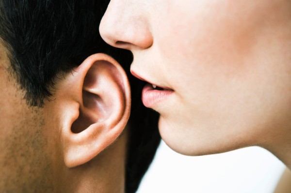 woman whispering in man's ear, close up