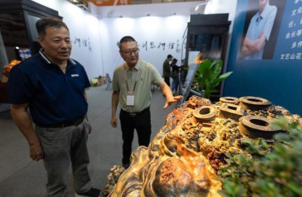 福建省工艺美术大师杨明正在介绍他的新作品——以南靖“四菜一汤”田螺坑土楼群为原型的寿山石雕。福建日报记者 施辰静 摄