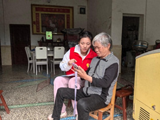 图为志愿者教老人使用智能手机