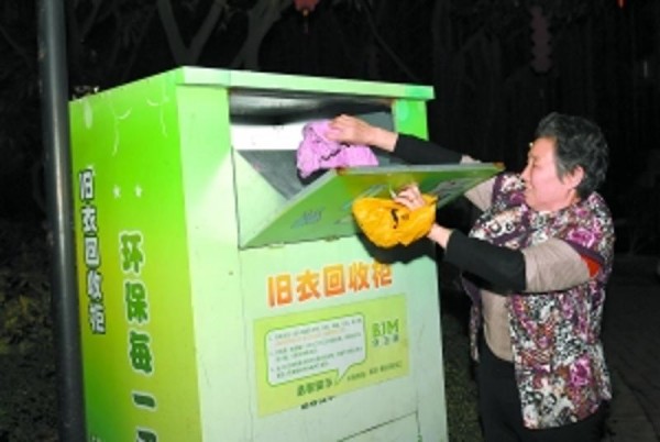 街坊在向旧衣回收箱里放旧衣服。广报记者乔军伟 摄