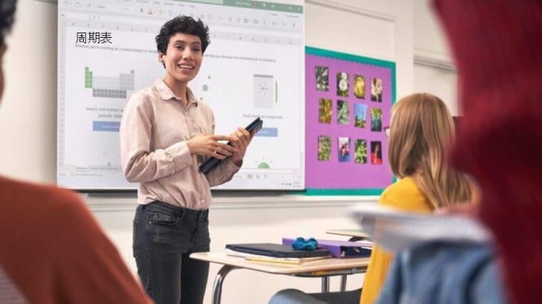 在平板电脑模式下使用 Lenovo 300w 在教室前演示的 K-12 女教师。 三名学生坐在单独的书桌旁聆听演示文稿。