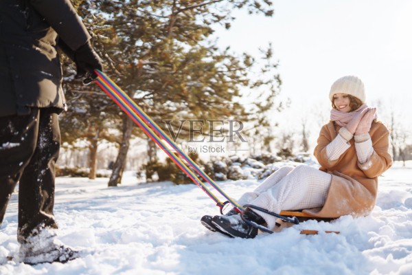 快乐的女人在冬天的森林里滑着雪橇。Сouple在冬天的大自然中玩耍。假日、休息、旅游理念。照片摄影图片