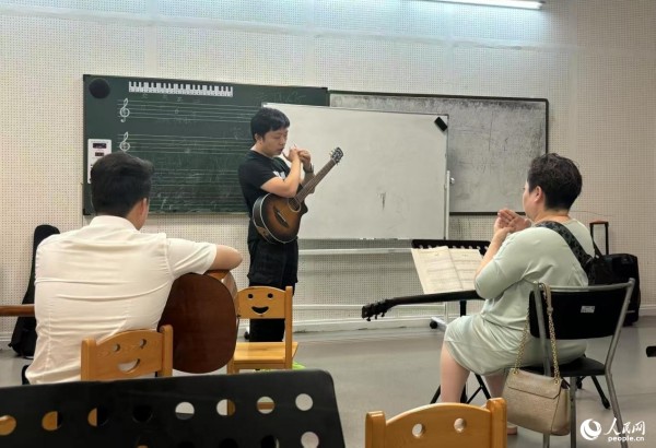 长沙青少年宫夜校，学员在专心学习吉他弹奏技巧。共青团长沙市委供图