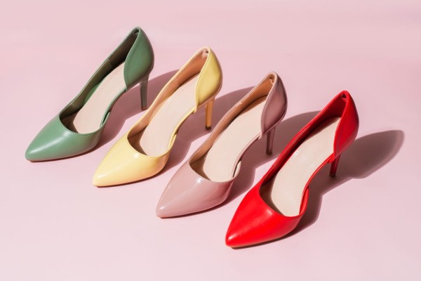 multicolored womens shoes stand in a row on vinyl pink background