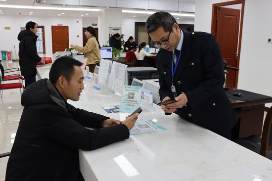 图2：全州烟草政务中心工作人员在指导消费者使用桂林烟草许可证前置服务系统 邓崇国摄