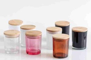 different colors of glass candle jars with wooden lids