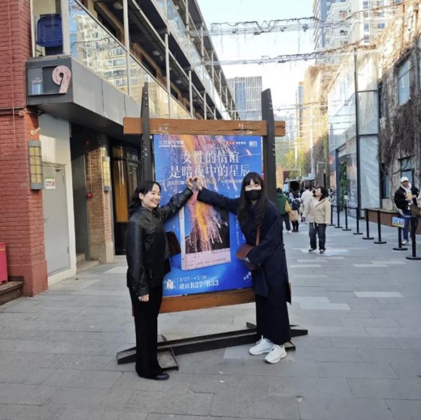 崔恩荣(左)与《明亮的夜晚》一书的韩文版编辑金娜利在步行街海报前合影。