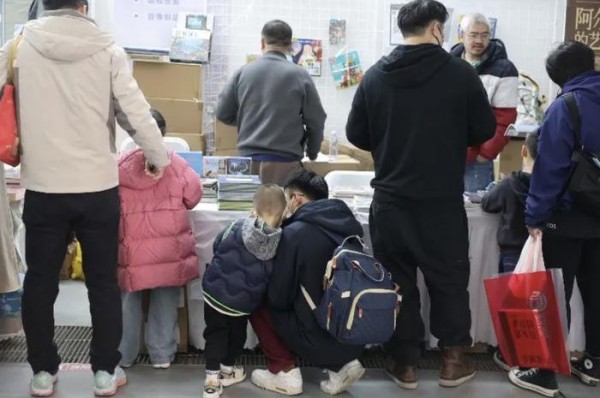 小朋友倚靠在家长身边阅读。新京报记者 王子诚/摄