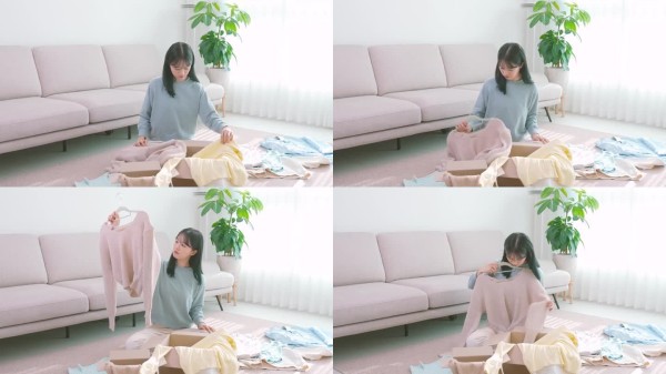 独自生活 - 一位年轻女性正在整理二手衣物并将其打包到快递箱中 / 韩国