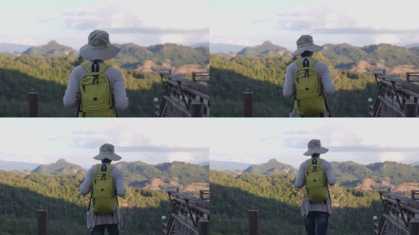 背着相机背包的男性旅行者，户外旅行生活方式与冒险概念。戴着帽子的背包客与游客一起参加绿色山脉之旅，感