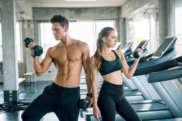 young couple of athletes doing muscle training with dumbbells at gym healthy lifestyle, exercising and people concepts
