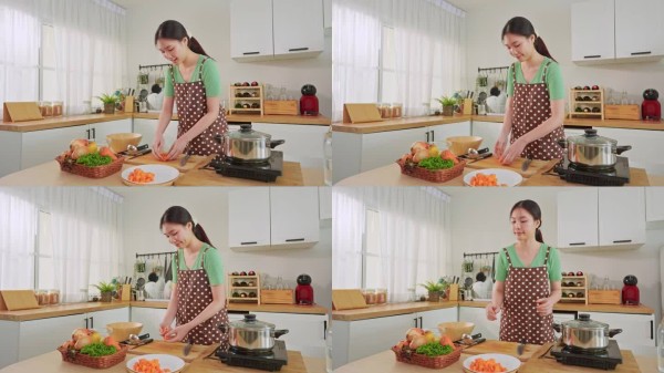 亚洲年轻女性在家中的厨房里早晨烹饪健康食品。迷人的家庭主妇感到快乐，享受为早餐准备煮汤的食材。