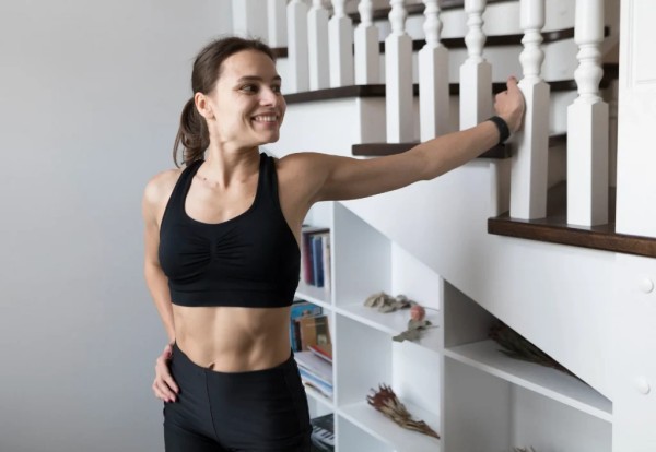 mujer estirando con la escalera de su casa