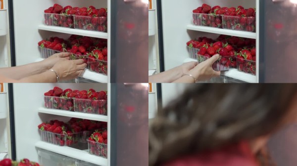 新鲜感揭晓：手展示冰箱中装满成熟草莓的篮子