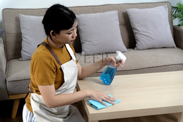 一位年轻女性正在清理客厅里的桌子照片摄影图片