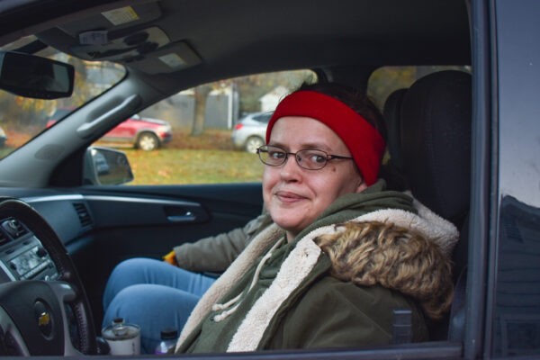 Woman smiling while sitting in her car at a Mobile Pantry