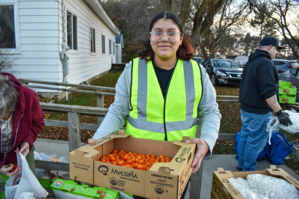 Volunteer holding up a box of tomatoes