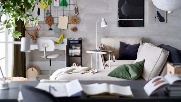 客厅角落里有一个小工作台,一个笔记本电脑支架放在一张带有靠垫的单人沙发旁边,还有一张贵妃椅。