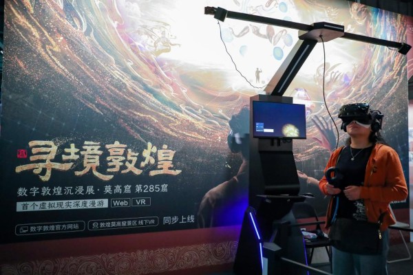 2024年9月22日，在敦煌研究院“典范”“高地”建设成果展上，游客借助VR设备沉浸式游览莫高窟第285窟虚拟场景。新华社记者 郎兵兵 摄