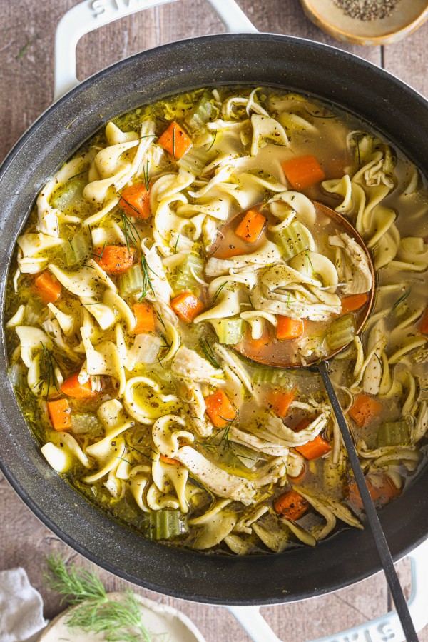 close up pot with chicken soup and a ladle.