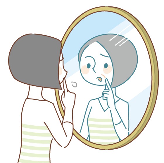 鏡の前でほうれい線などのシワを気にしている40代の女性