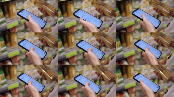 手握着环保面包棒和一部部分勾选了购物清单的手机,强调了有意识的消费主义。非常适合可持续发展、健康或食