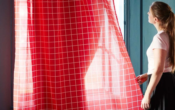 阳光透过两幅透明轻薄的宜家 ROSALILL 欧塞利尔 窗帘照射进来，窗帘以红色为背景颜色，饰有白色线条。