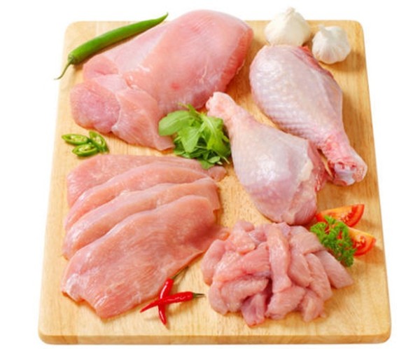 鸡腿和大葱摆放在木质砧板上,旁边有调料瓶和刀具