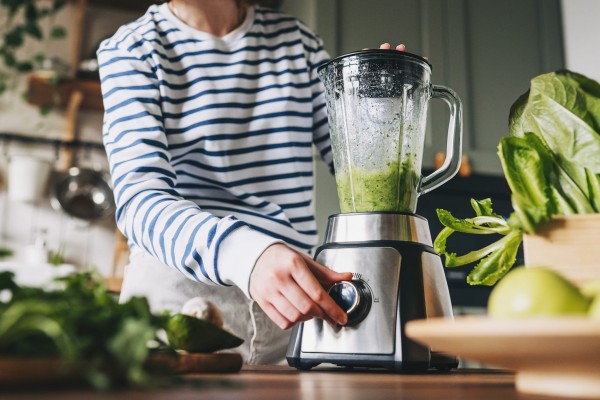 healthy eating, cooking, vegetarian food, dieting and people concept close up of young woman with blender and green vegetables making detox shake or smoothie at home