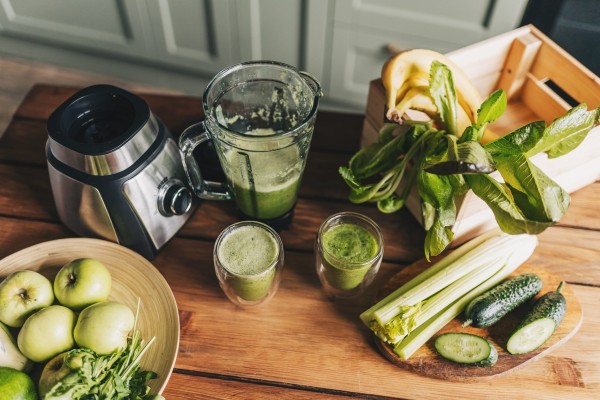 healthy green smoothie with banana, spinach, avocado and chia seeds in a glass bottles on a rustic background
