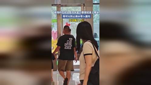 商场的工作人员为外卖小哥擦拭身上雨水