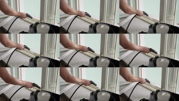 清洁服务人员使用蒸汽清洁器清洗窗框,特写镜头。方便有效的日常家务、维护任务的概念。