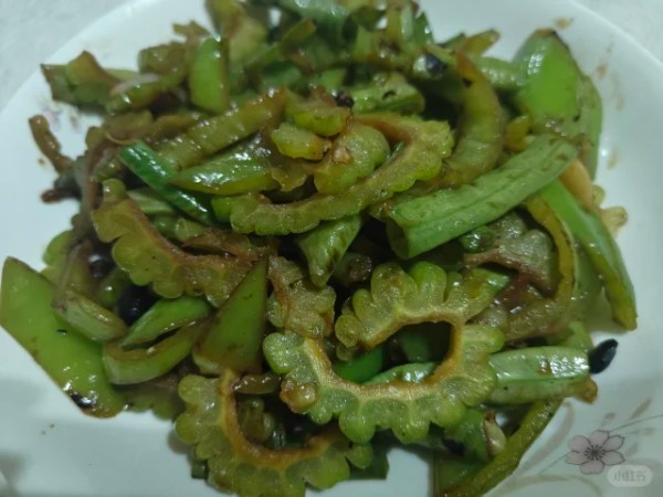 成品苦瓜炒豆角盛放在浅色瓷盘中的俯拍图