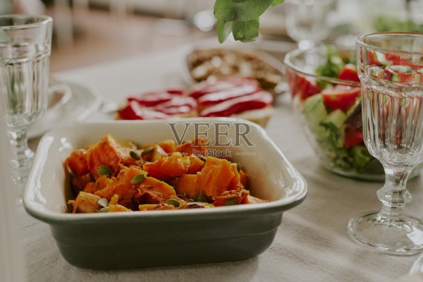 节日餐桌上盛放的烤南瓜沙拉特写，配有种子照片摄影图片